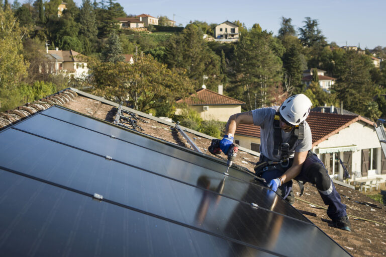 homme installant des panneaux solaires sur un toit