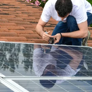 homme posant un kit panneaux solaire sur un toit