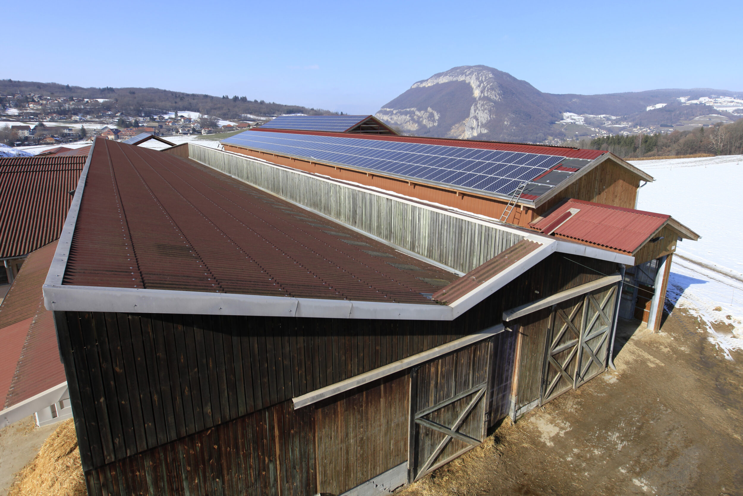 grange enneigée avec des panneaux solaires sur le toit