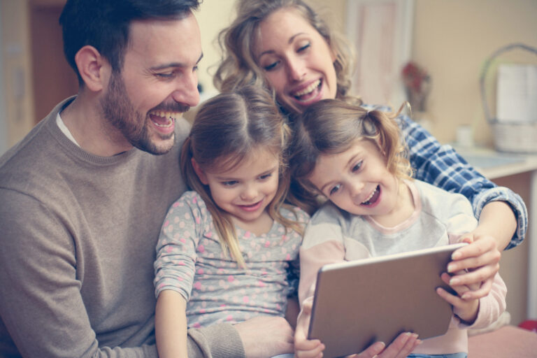 Un homme et une femme avec leur deux enfants devant une tablette numérique